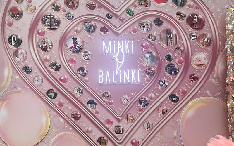 A visually striking display features the names "Minki" and "Balinki" illuminated in white neon against a pink backdrop adorned with a large heart shape. Surrounding the heart are various circular images, creating a vibrant and artistic collage.